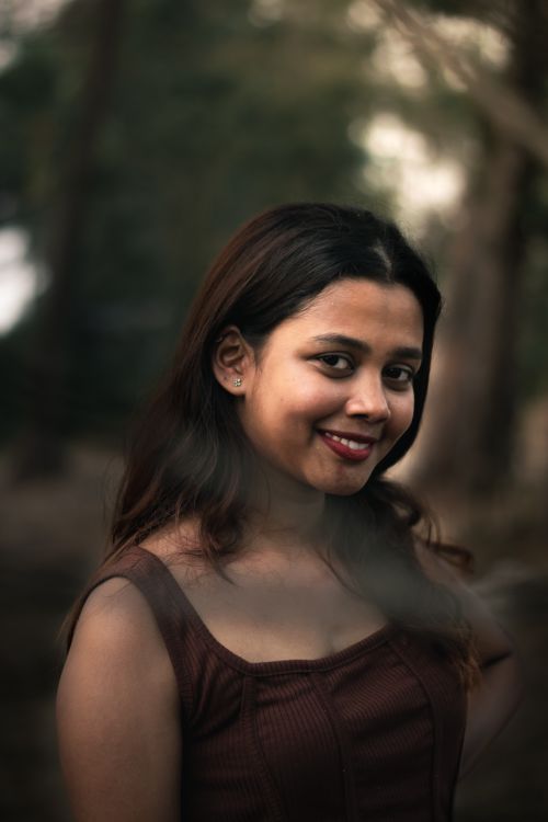 Free Portrait of a smiling woman posing outdoors with a subtle and natural background. Stock Photo