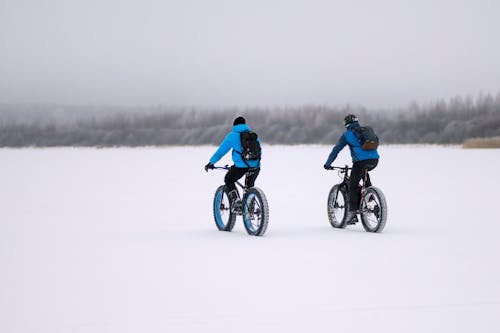 People Riding Bikes in Snow in Winter Countryside