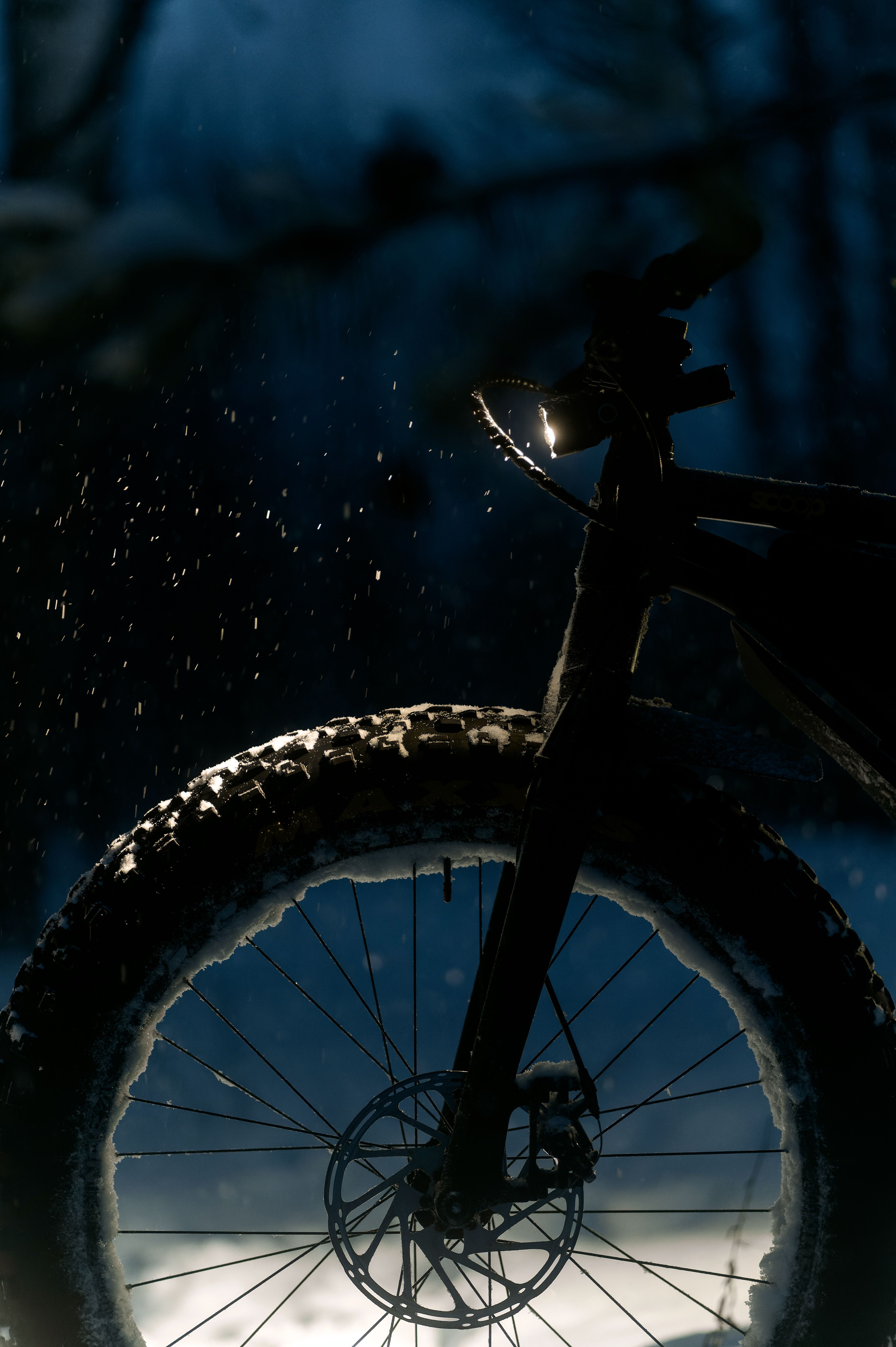 Closeup of a bicycle wheel in a snowy winter night with falling snow.