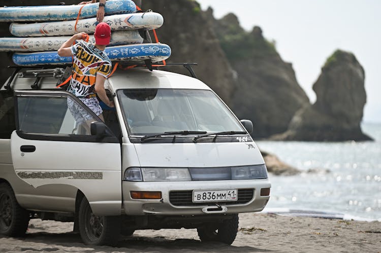 Surfboards On Van Roof On Seashore