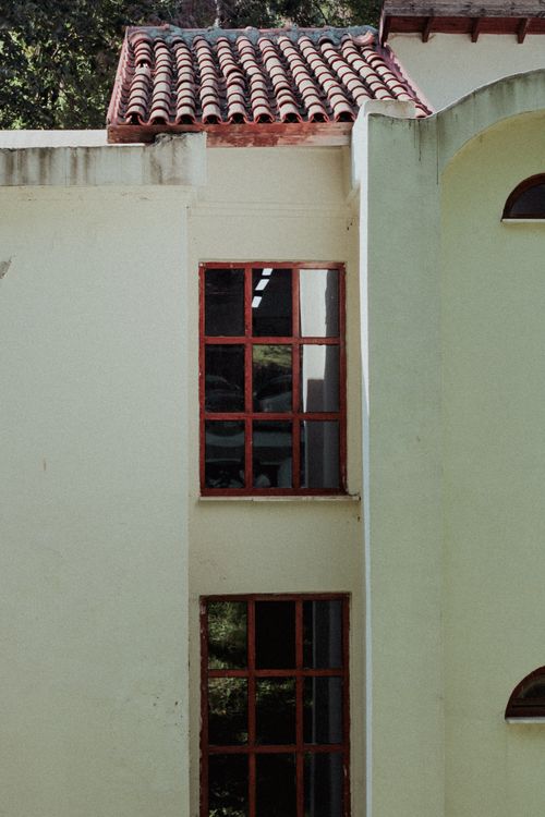 Free Elegant residential facade featuring red framed windows and classic roof tiles. Stock Photo