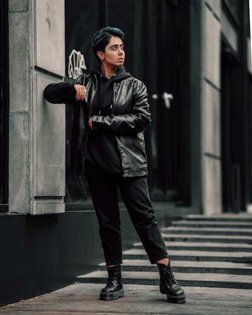 Person in Leather Jacket and Black Pants Posing on Sidewalk
