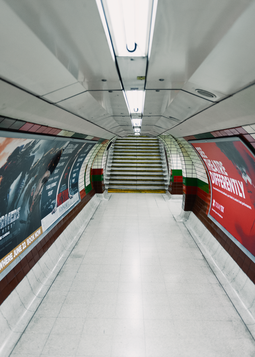 Free Empty London subway tunnel with colorful posters, leading to stairs. Stock Photo