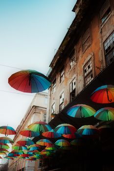 Vibrant umbrellas decorate a street in Lisbon, Portugal, adding color to urban architecture.