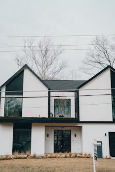 Contemporary residential building with a sleek black and white exterior and large windows.