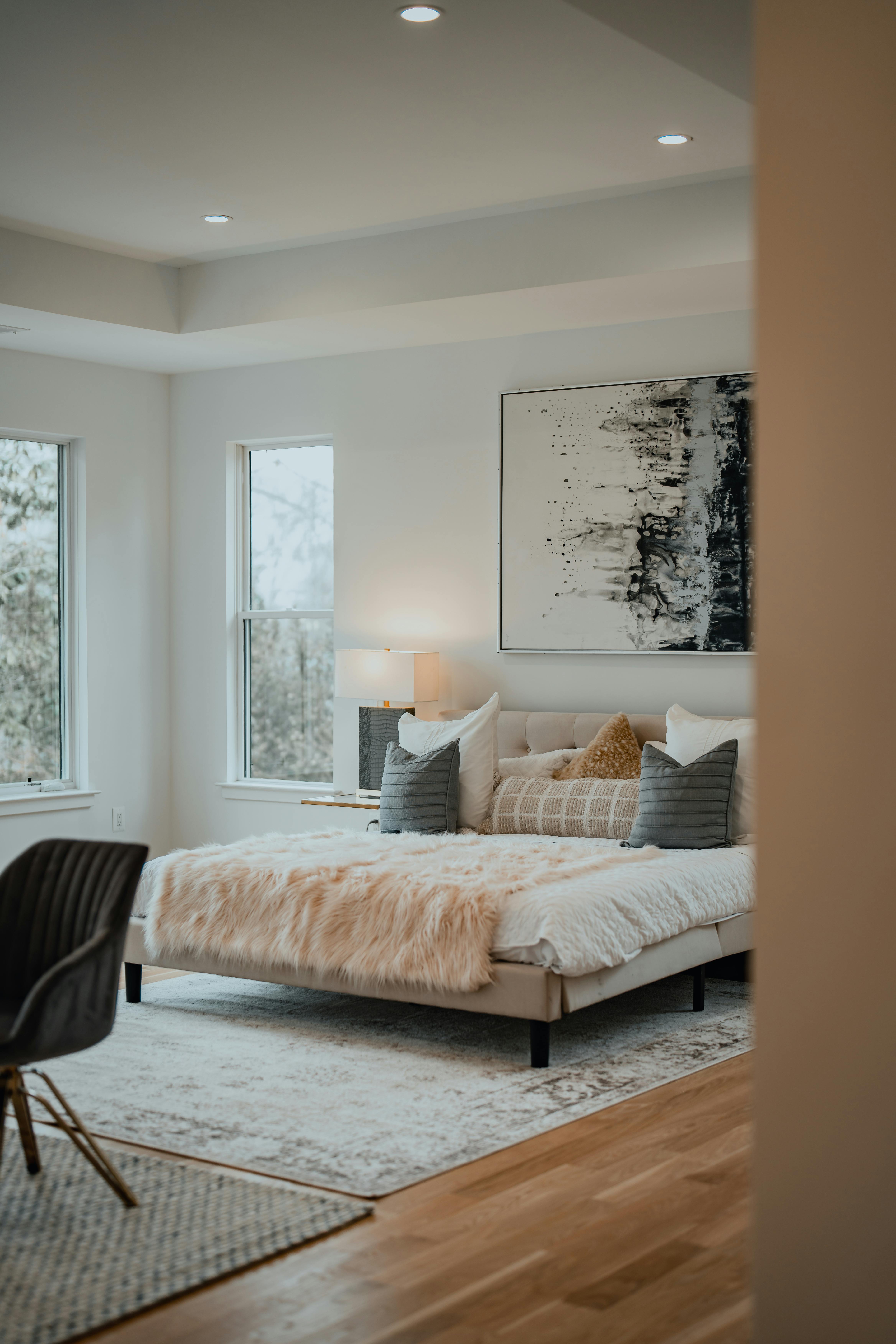 Stylish bedroom interior with soft lighting and elegant decor, featuring cozy bedding and abstract wall art.