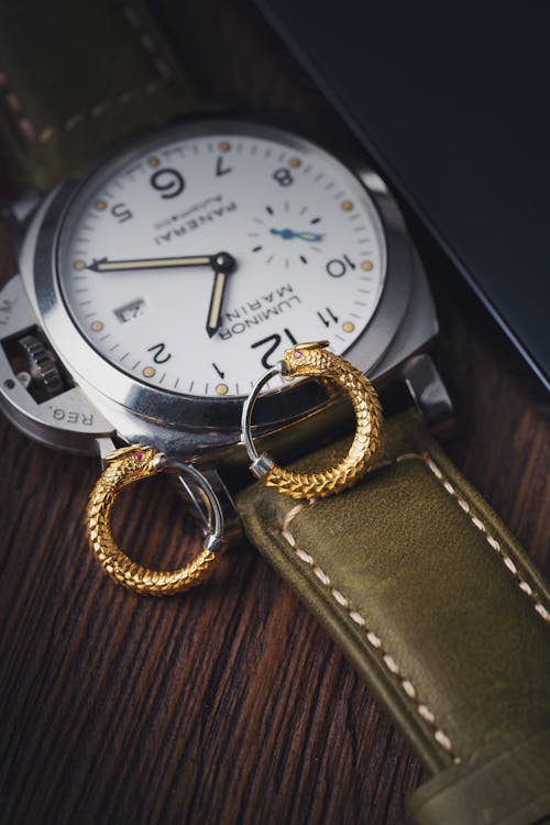 Close-up of Gold Earrings in Dragon Shape Lying on a Wristwatch 