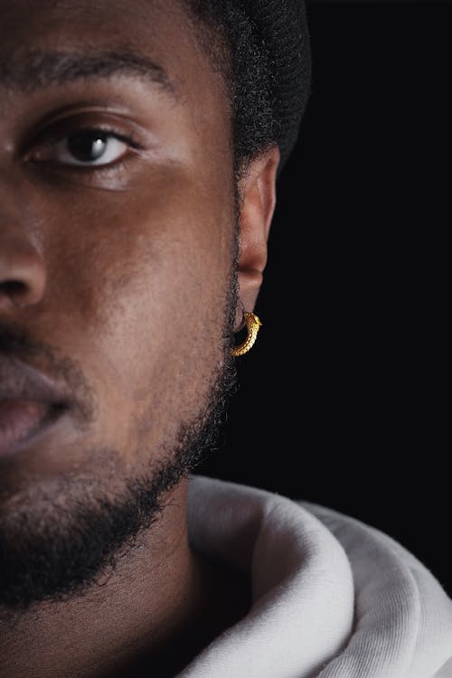 Close-up Portrait of Half of the Face of a Young Man with a Beard, Wearing a Gold Earring 