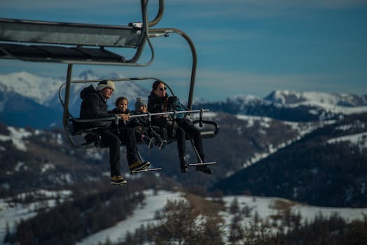 Family having fun on a ski lift with snow-covered mountains in the background during a sunny winter day
