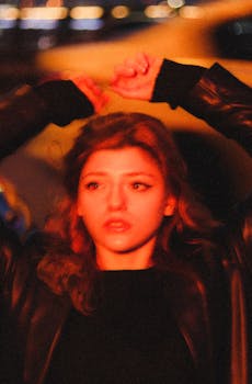 Blurred artistic portrait of a woman in a leather jacket with warm night lighting.