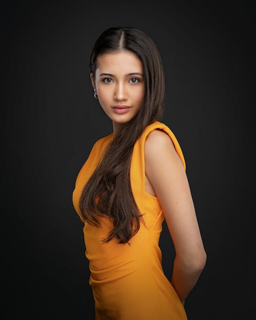 Young Woman in an Orange Dress Posing in Studio 