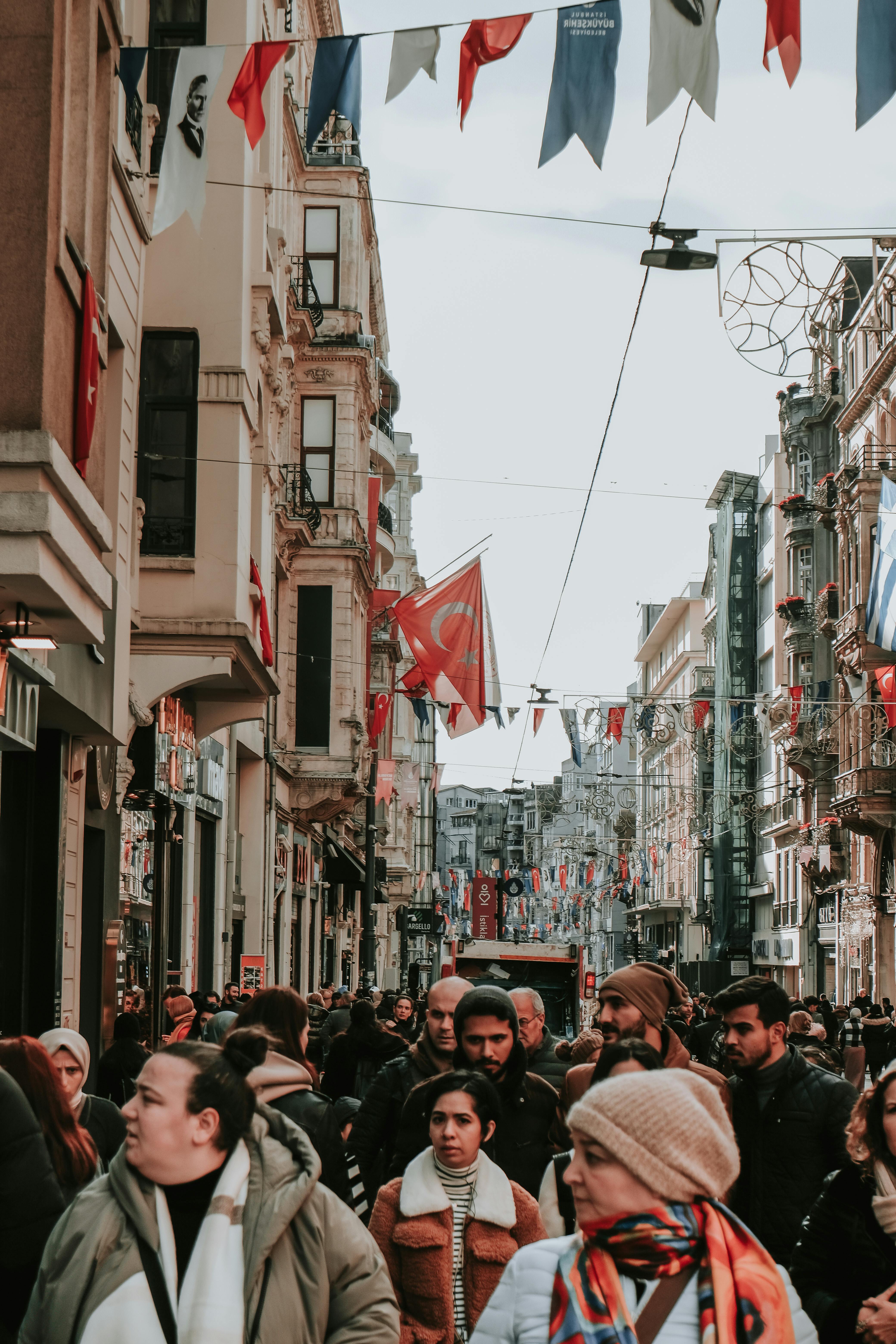 people walking down a street with flags hanging from the buildings