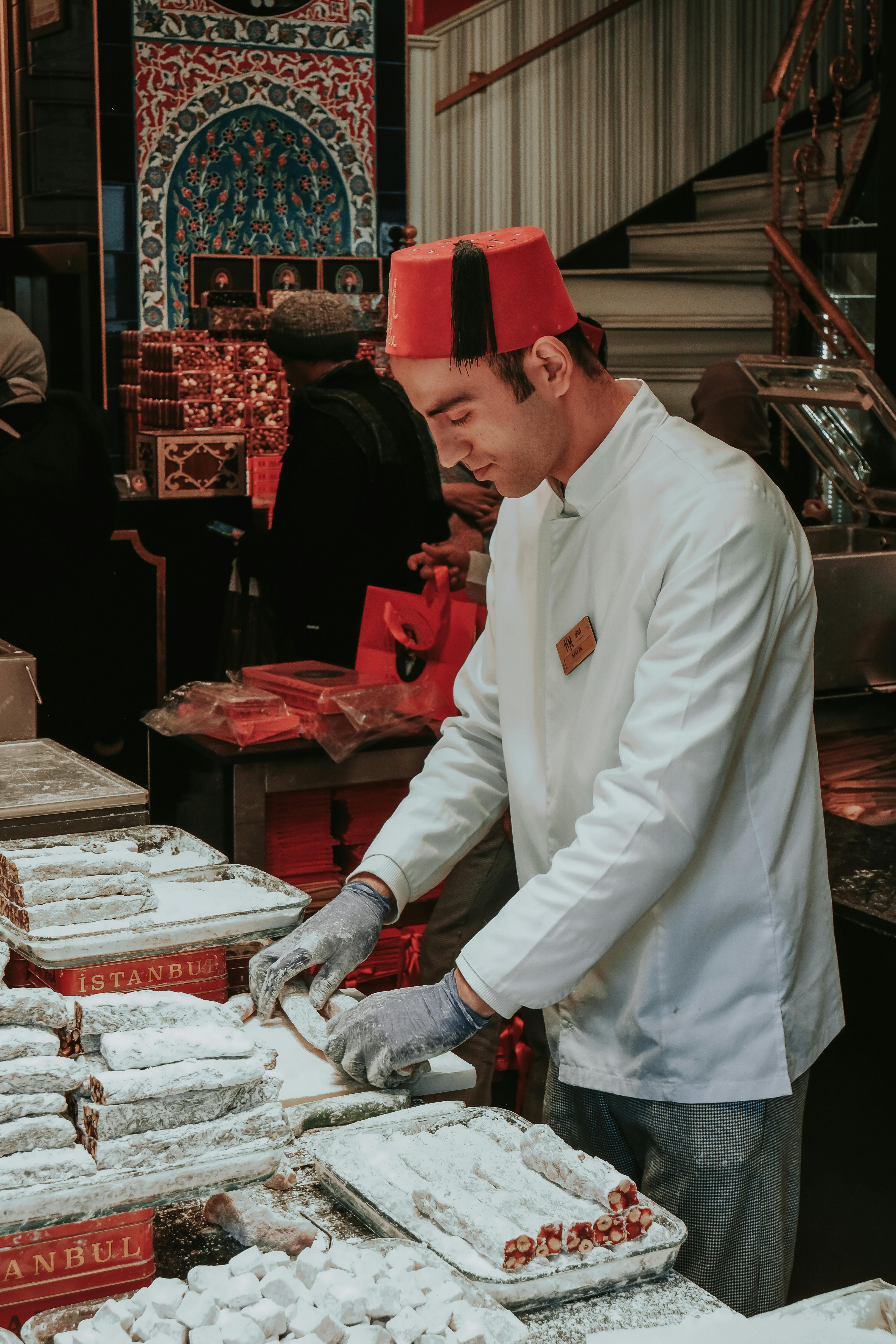 a man in a red hat and white shirt is preparing food