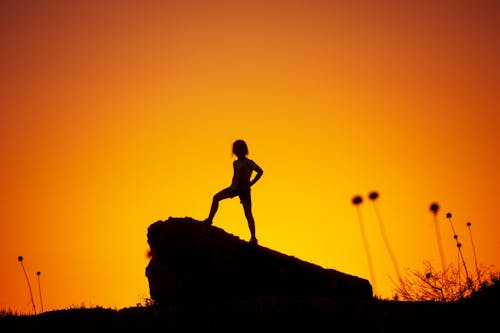 Silhouette Photography Of Kid Standing On Rock