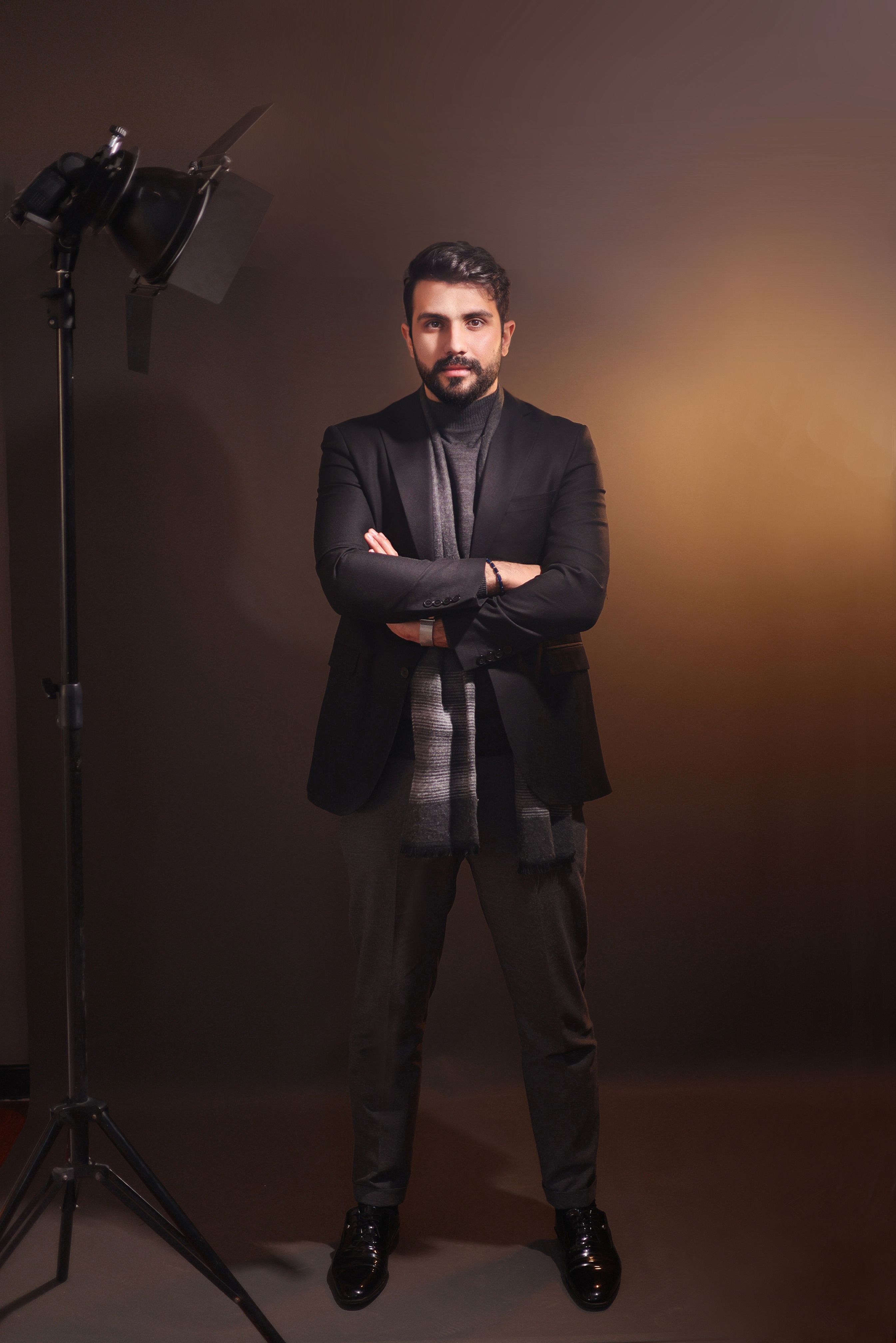 Elegant male model posing confidently in a studio wearing a stylish suit. Fashion photography with a modern look.