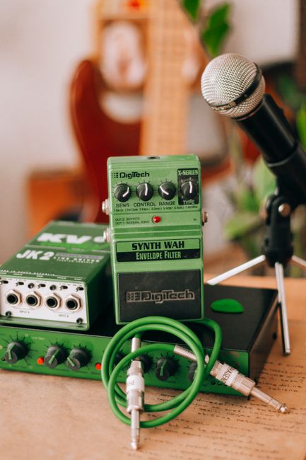 Close-up of audio equipment featuring synth wah, cables, and microphone in a studio setting.