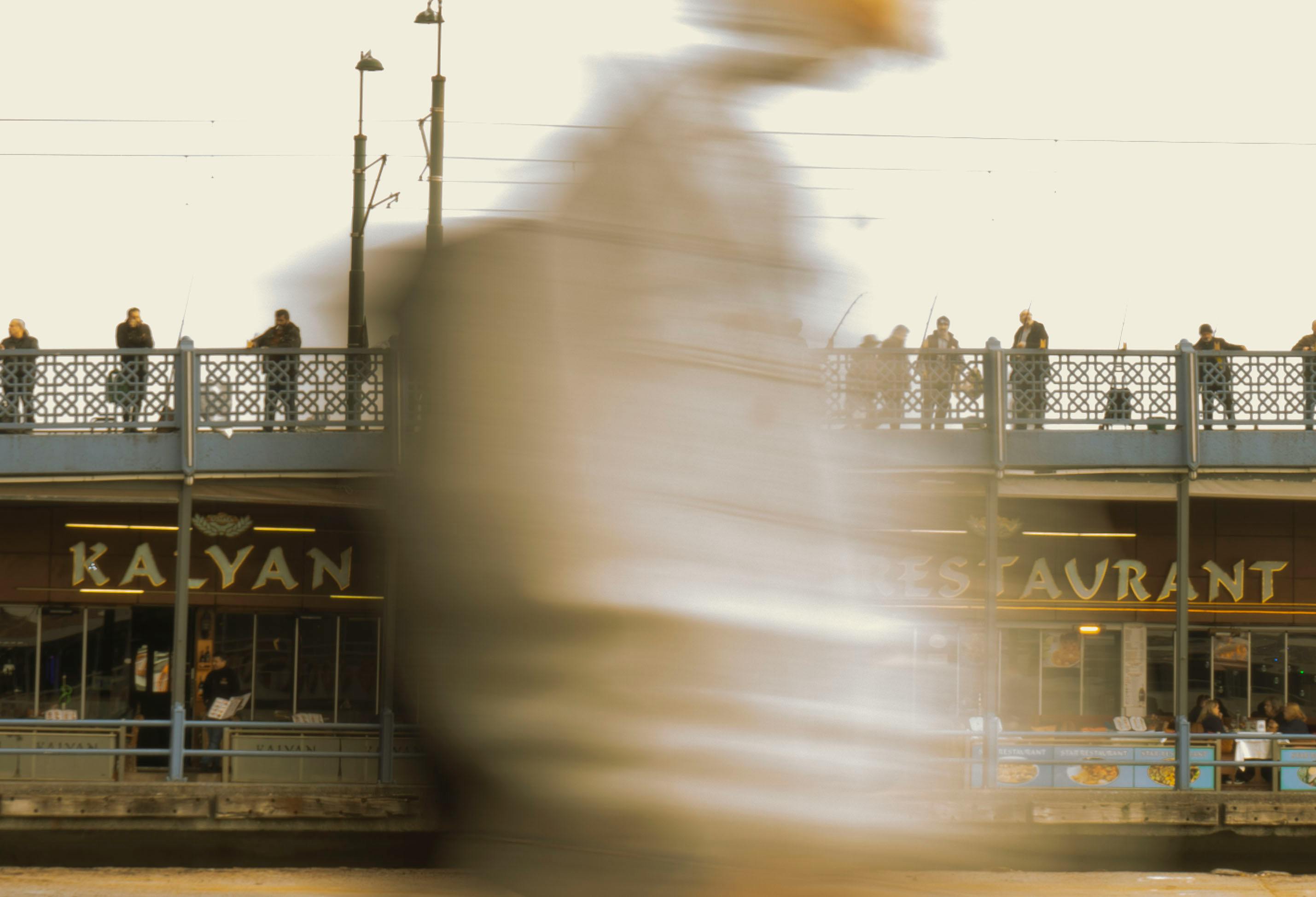 Motion blur of a person walking near a bridge in Istanbul, Turkey.