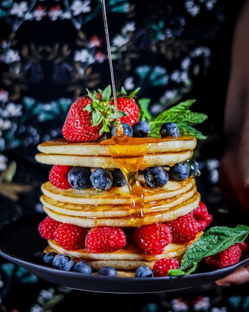 Photo of Honey Pouring on a Layered Pancake with Fruits
