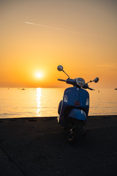 A Motor Scooter Parked on a Beach at Sunset 