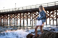 日落时分，一名身穿牛仔夹克的女子站在加维奥塔码头的岩石旁，欣赏海景