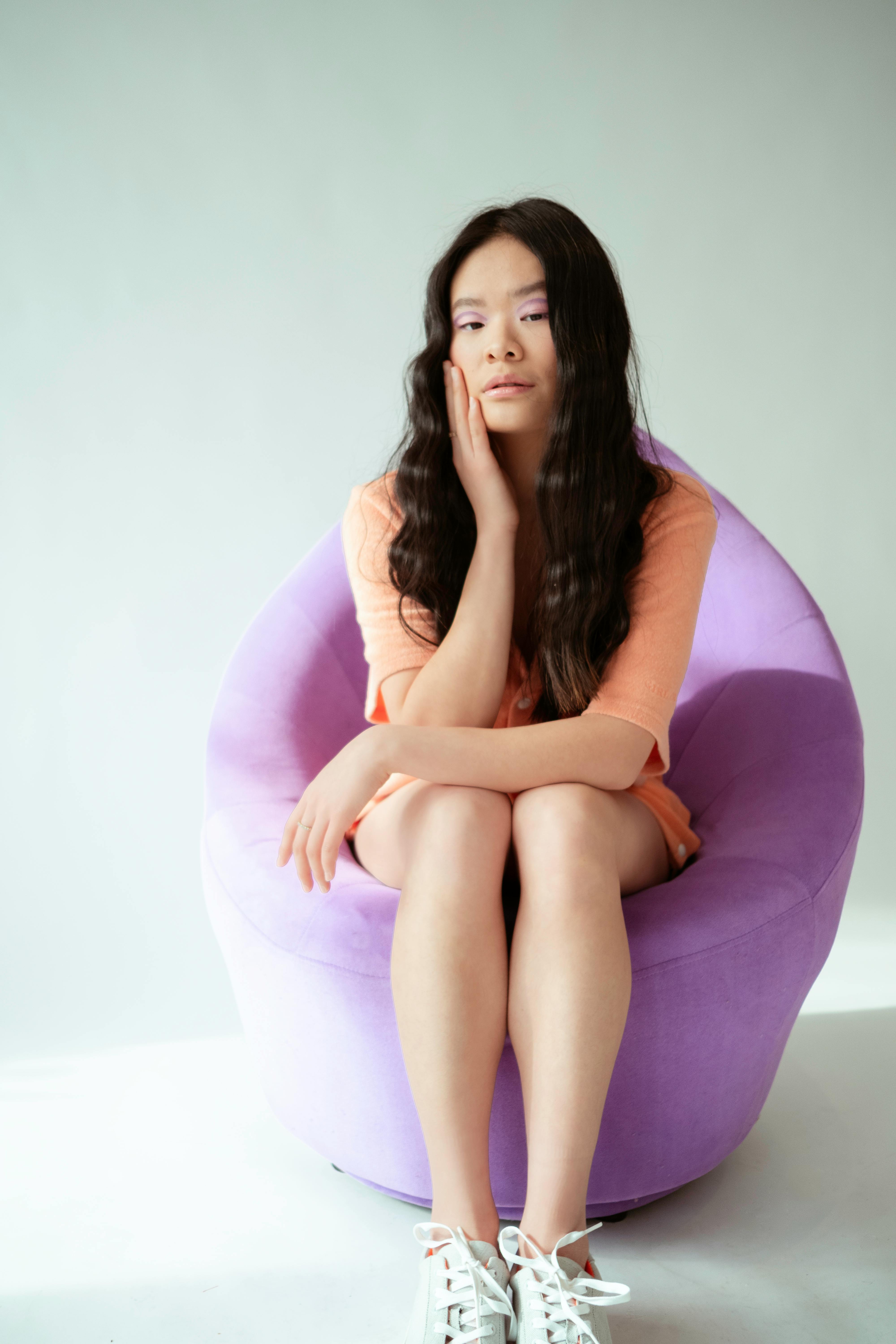 一位时尚的年轻女子坐在室内一把充满活力的紫色椅子上