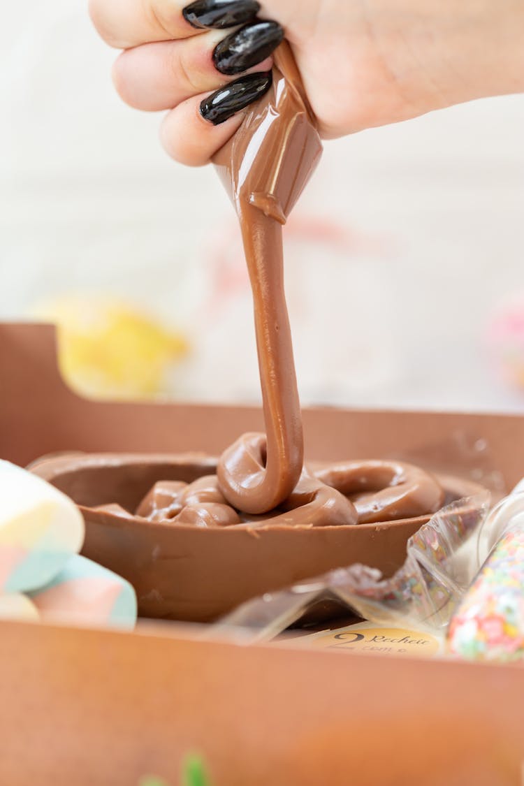 Female Hand With Black Manicure Squeezing Chocolate