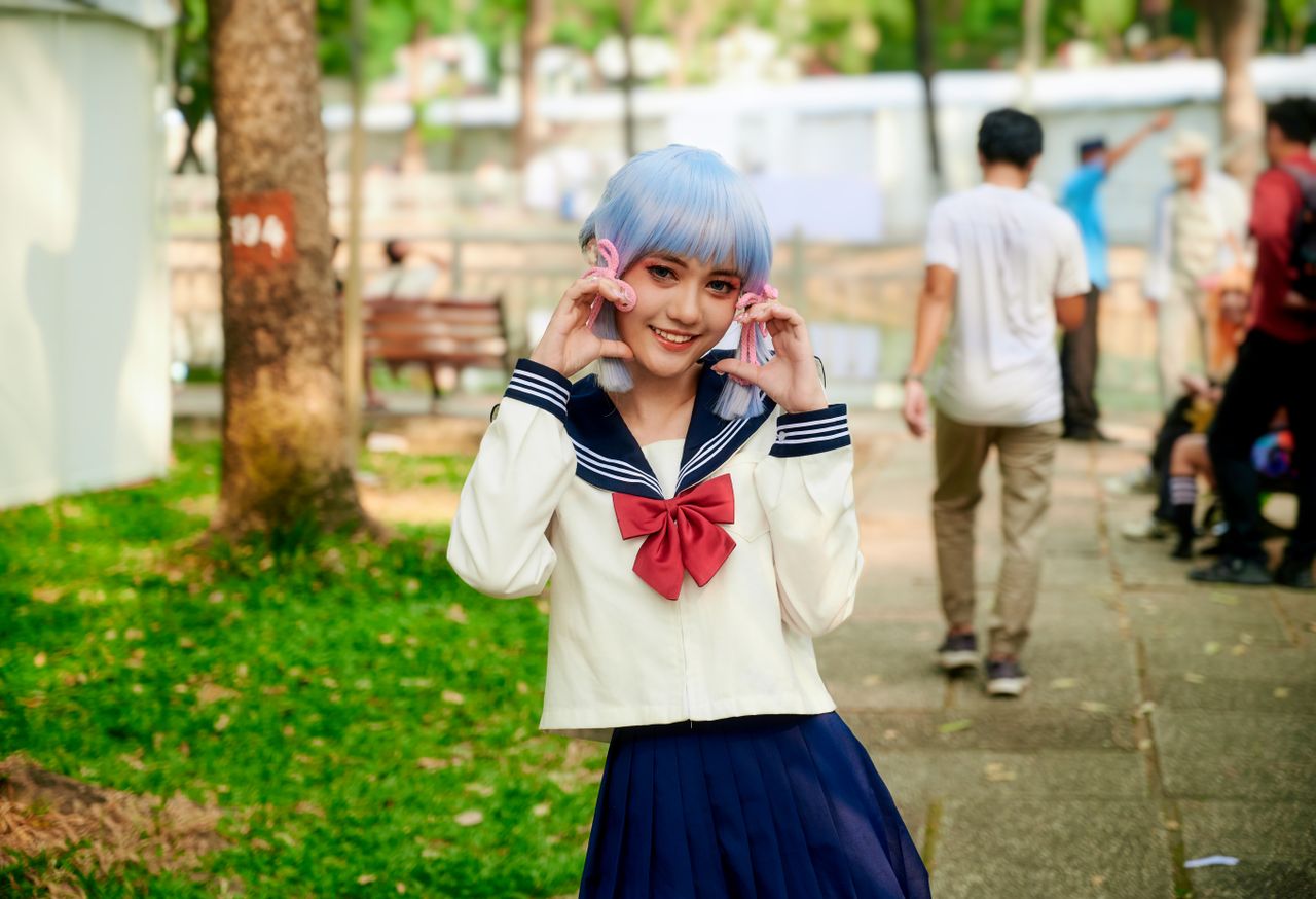young woman in blue wig and sailor costume enjoying an outdoor anime f