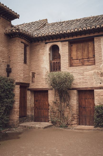 A rustic house featuring a traditional brick facade, wooden doors, and a tiled roof. Perfect for architecture enthusiasts.
