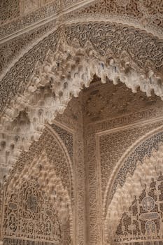 Detailed arabesque architectural design in Alhambra, Spain showcasing Islamic art style.