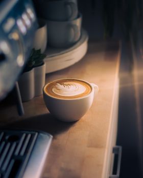 Warm and inviting cappuccino with frothy art, brewed in a stylish cup on a wooden countertop.