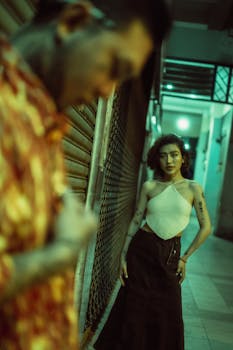 A fashionable Asian couple shares an intimate moment on a vibrant city street at night.