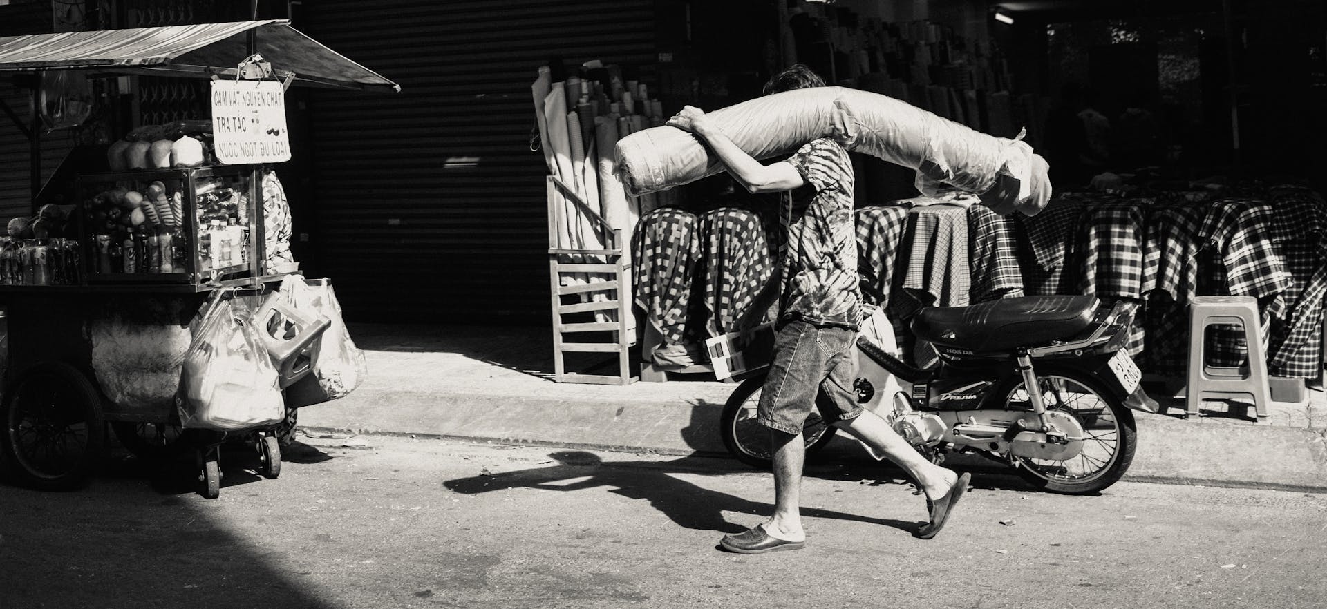 A man carries goods in a bustling street market, highlighting daily life.