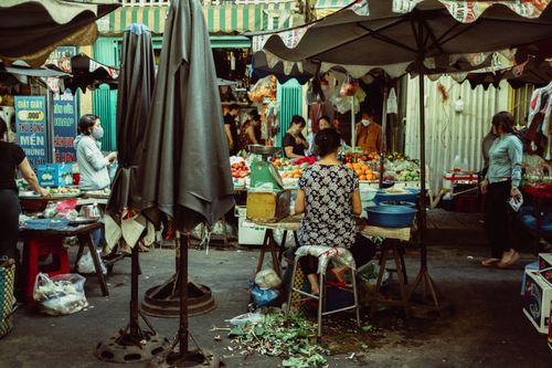 Free A vibrant outdoor market with multiple vendors selling fruits and vegetables, bustling with customers. Stock Photo