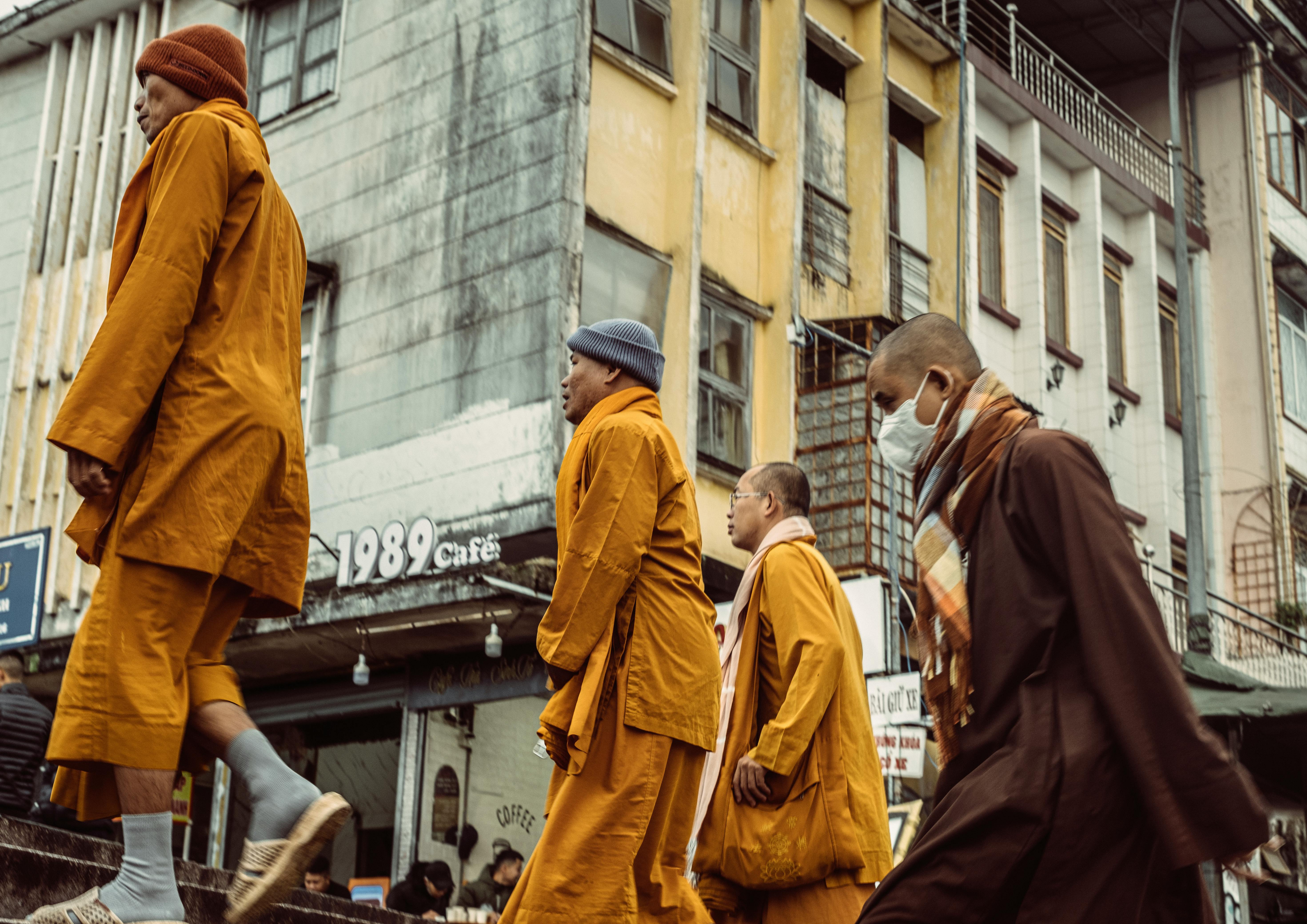 Monks in traditional robes navigate a bustling city street, showcasing urban culture.