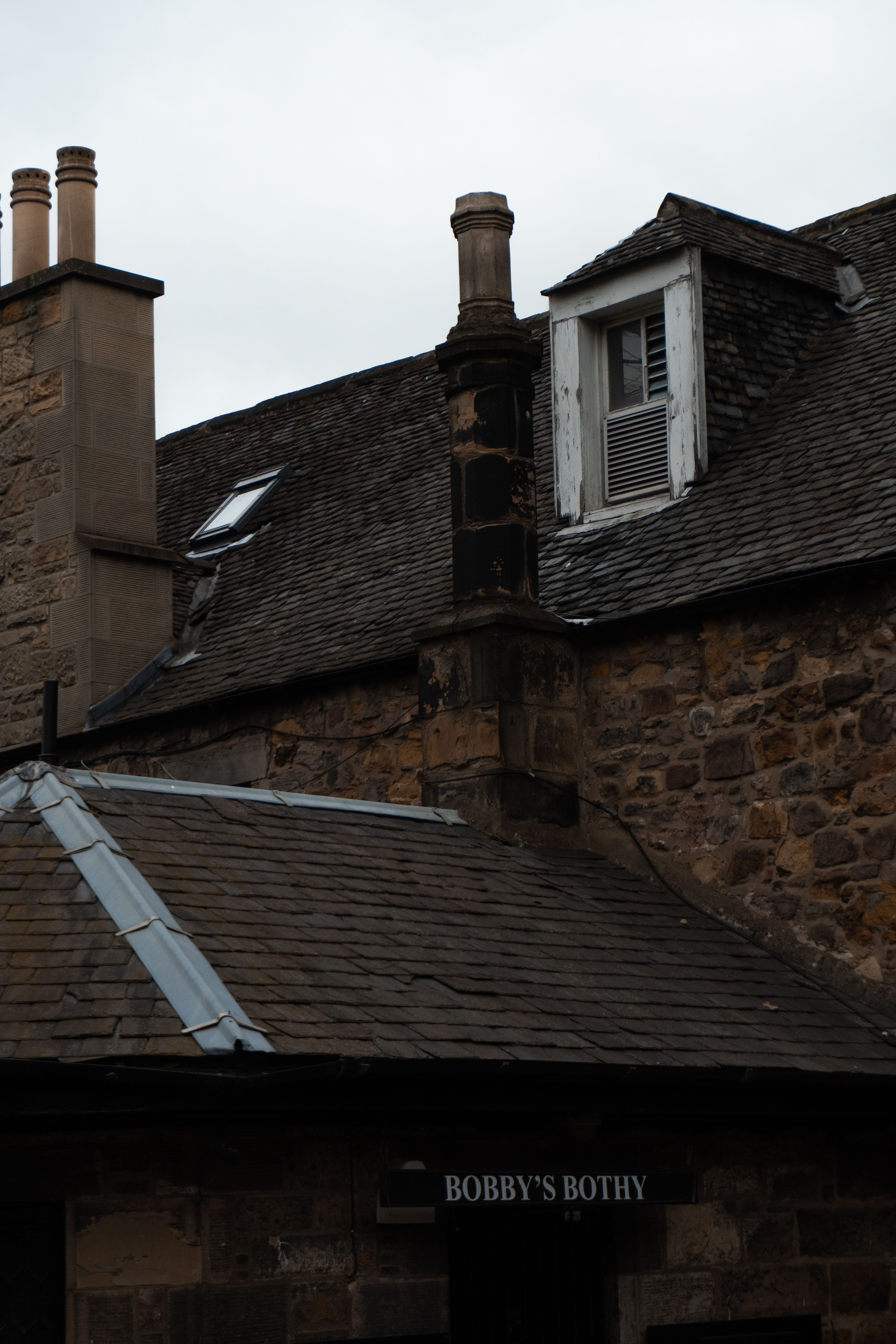 A row of historic stone chimneys against an overcast English sky, photographed at close quarters.
