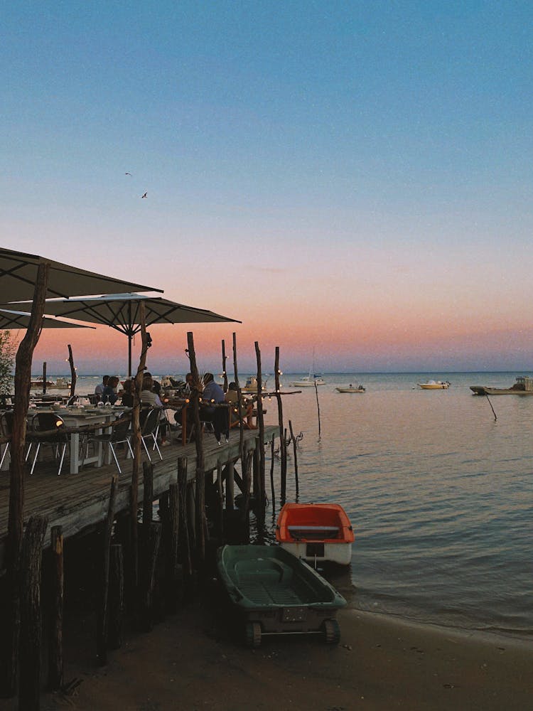 People Sitting In Seaside Restaurant At Sunset