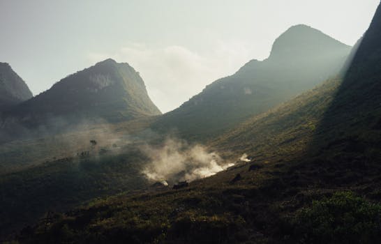 Captivating misty mountain landscape with sunlight and smoke at dawn, showcasing natural beauty.