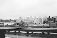 一张黑白照片，拍摄了雾中的城市景观，前景是工业建筑