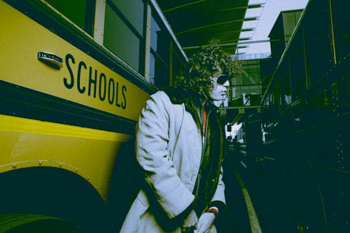 Man with Full Makeup Standing next to School Bus