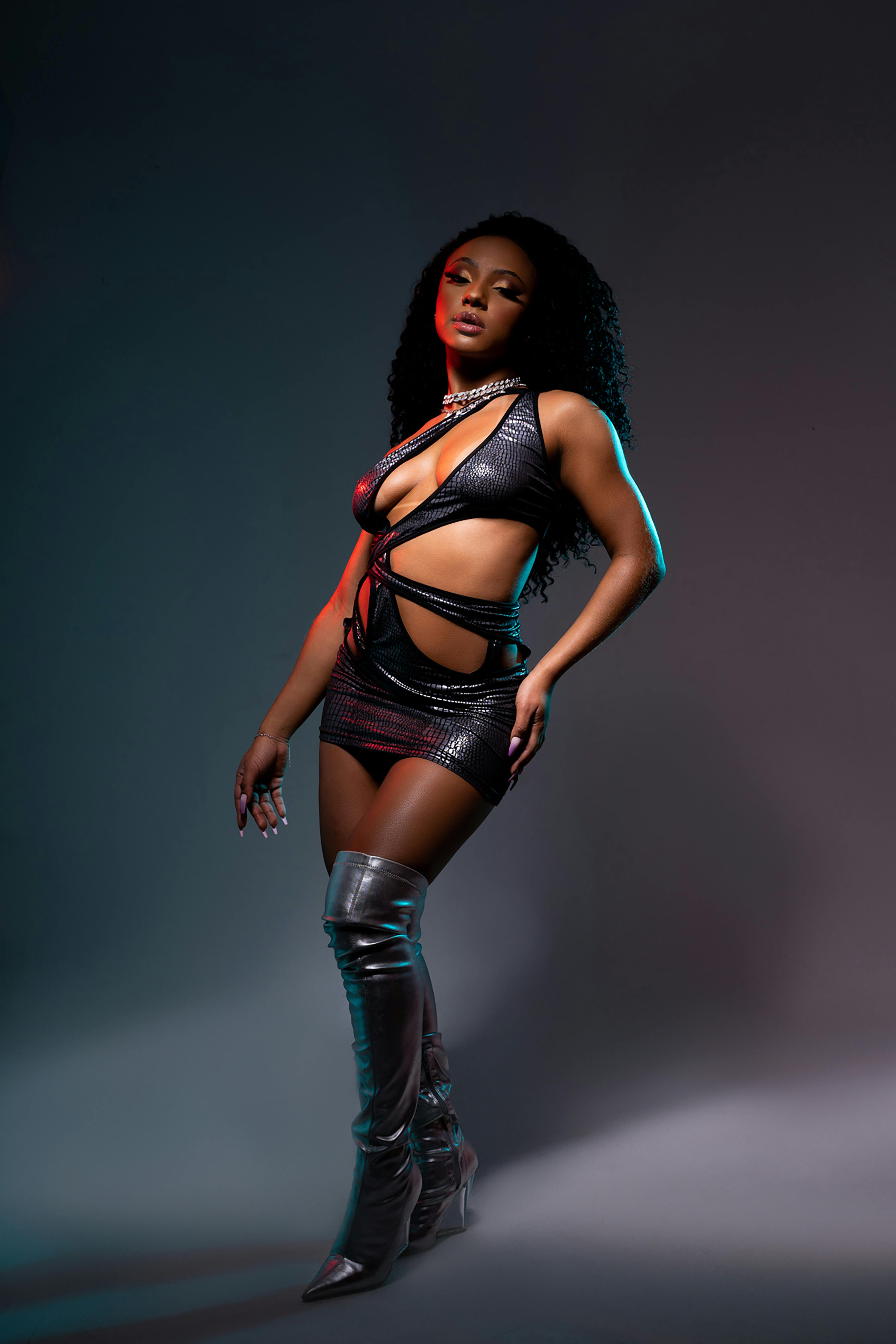 Free Fashion model in a studio wearing a stylish outfit and silver boots, showcasing modern elegance. Stock Photo