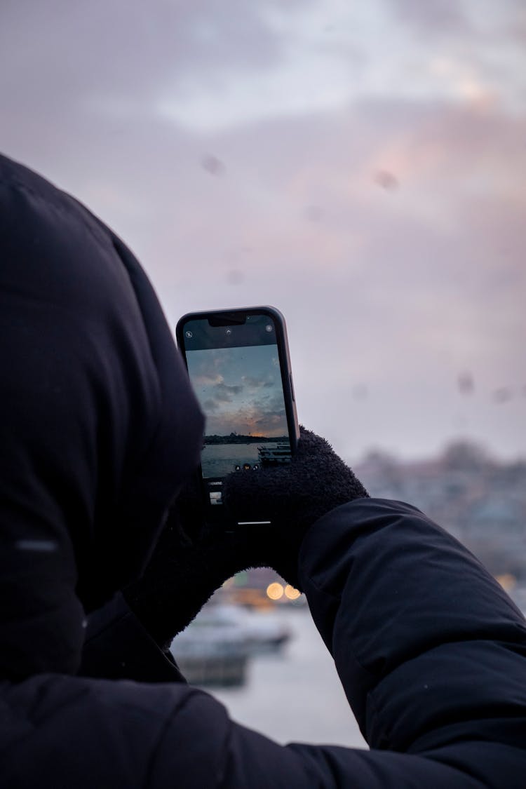 Man Taking A Photo Of A Winter Sunset With His Phone