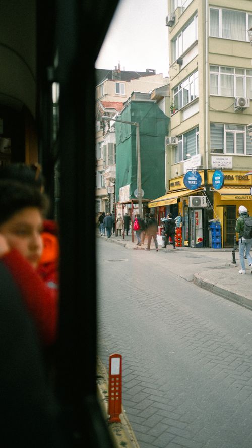 Free View of İstanbul street through tram window capturing daily urban life with pedestrians and buildings. Stock Photo