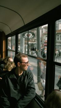 A man wearing sunglasses looks out the window of a tram in Istanbul, capturing urban life.