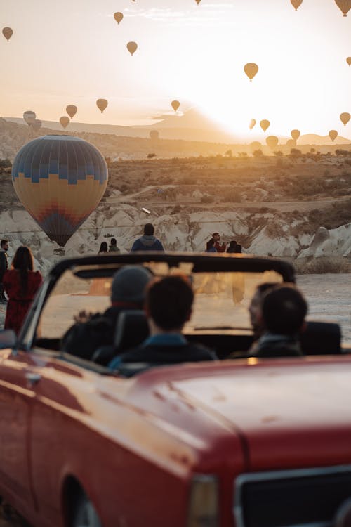 People in Vintage Car Watching Hot Air Balloons