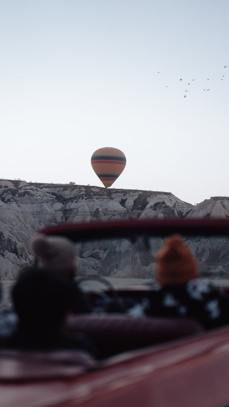 People In Vintage Car Watching Hot Air Balloon