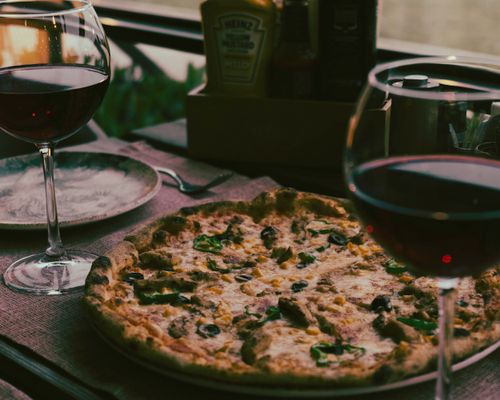 Free A delicious gourmet pizza served with red wine in a cozy indoor setting. Stock Photo