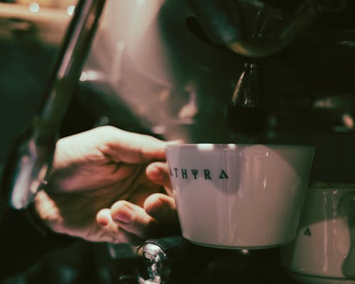 Close-up of Person Holding a Cup under an Espresso Machine