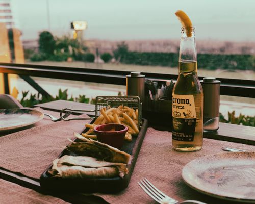 Free A relaxed outdoor dining scene featuring a beer bottle and fries on a table, perfect for casual meals. Stock Photo