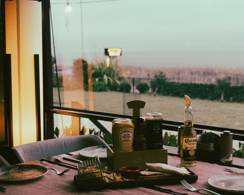 A brightly lit casual restaurant with several tables set, waiting for diners.