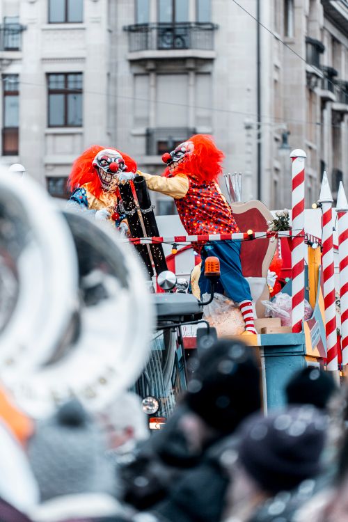 Free Two clowns engage in lively antics on a parade float during a street festival. Stock Photo